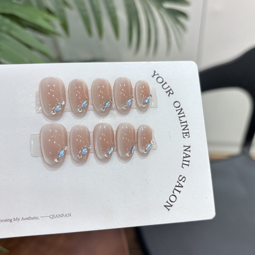 Nude cat-eye press-on nails with blue crystal-style tip accents