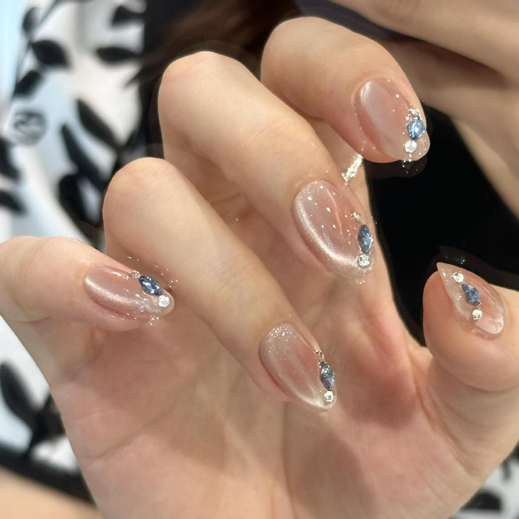 Nude cat-eye press-on nails with blue crystal-style tip accents