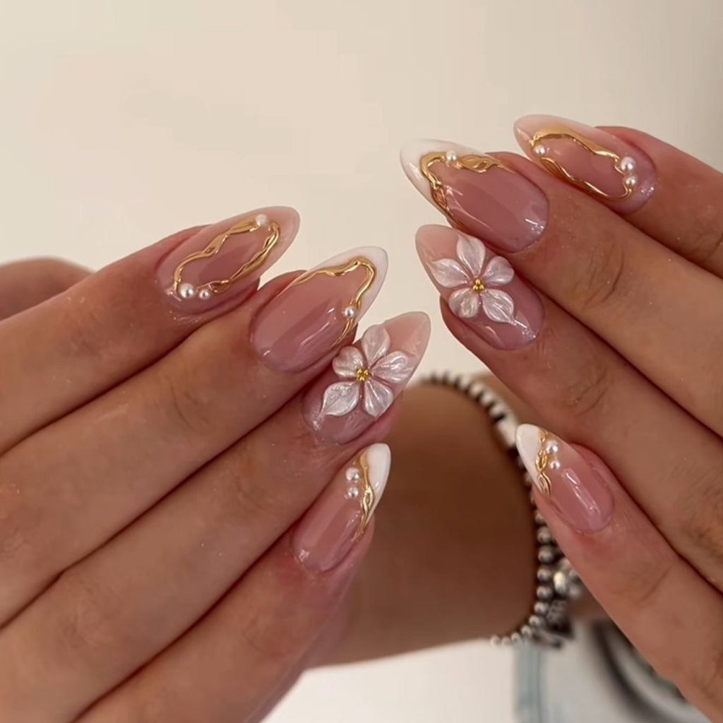 Blush-pink almond press-on nails with white flowers and gold details