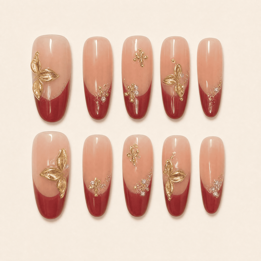 Burgundy French oval press-on nails with gold botanical embellishments