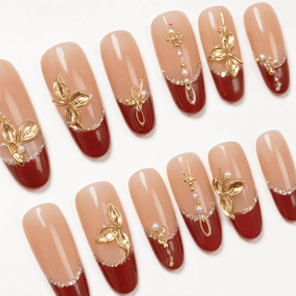 Burgundy French oval press-on nails with gold botanical embellishments