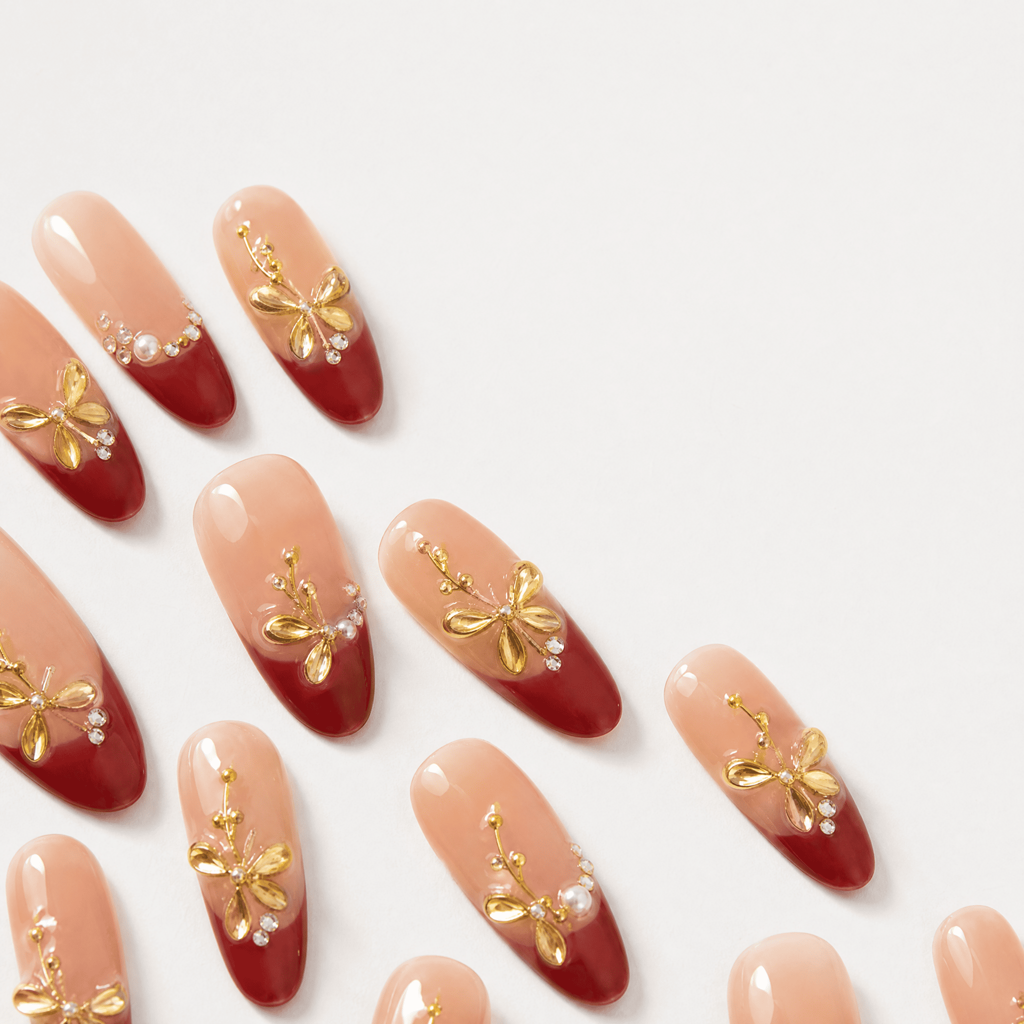 Burgundy French oval press-on nails with gold botanical embellishments