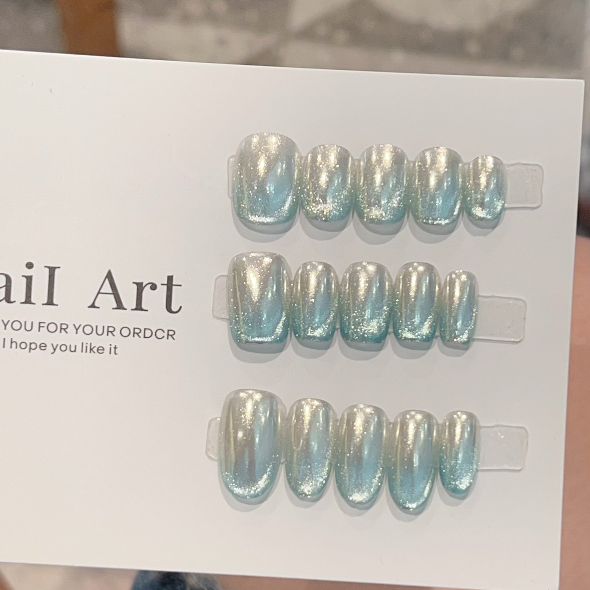 Icy-blue silver mirror cat-eye press-on nails worn on a hand