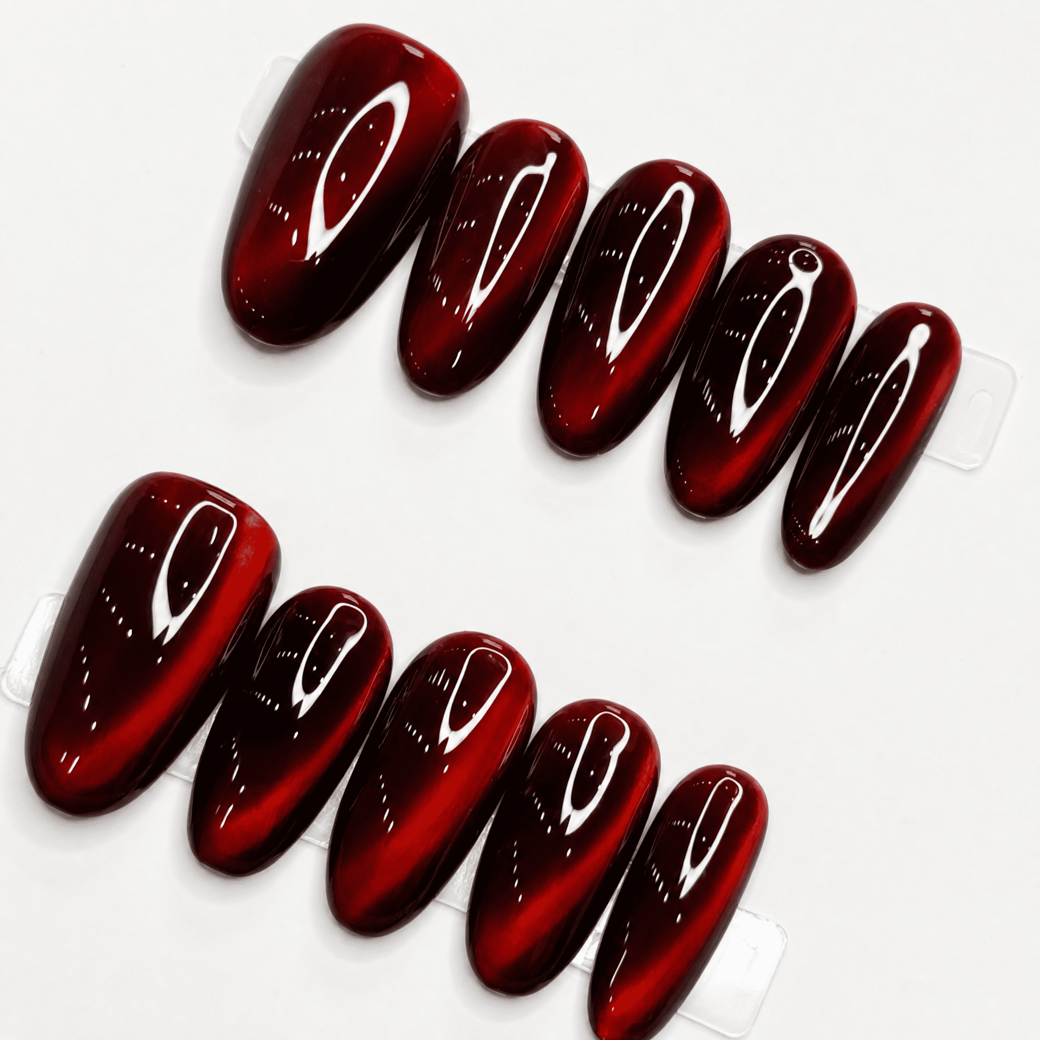 Ruby-red short-oval cat-eye press-on nails with reflective shimmer